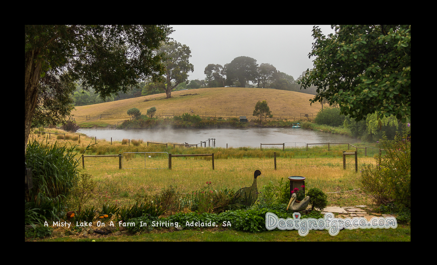 Misty scene in the Adelaide hills with a hill in the back with garden ornament in the foreground and a lake in the middle