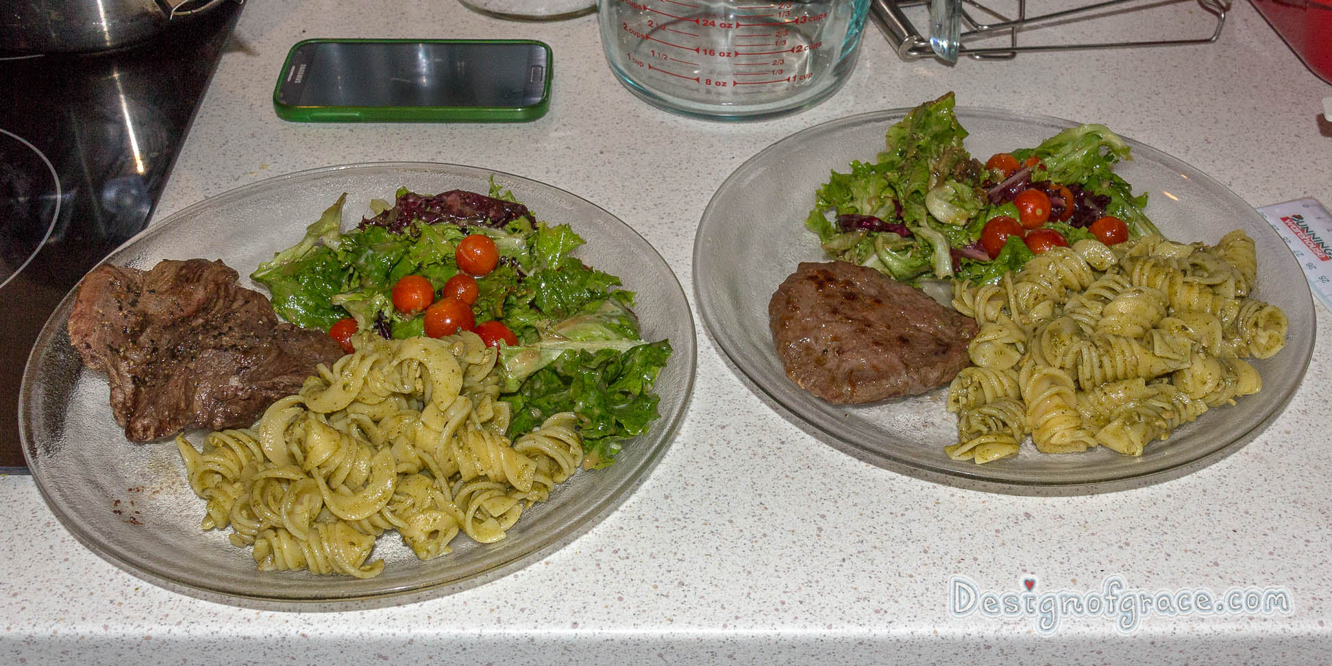2 plate of food with the kangaroo steak on the left and the patty on the right with pesto pasta and salad.