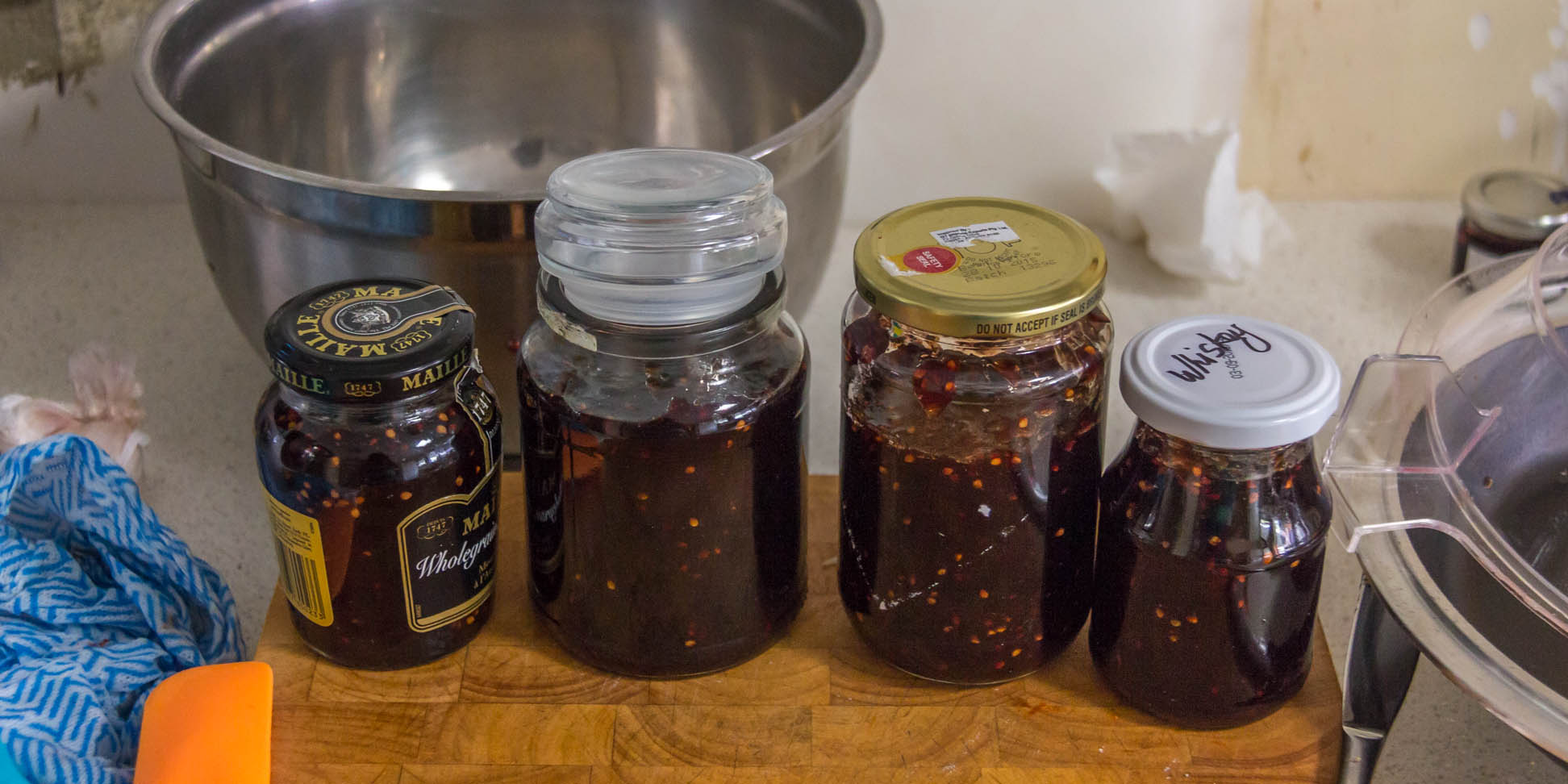 4 jars of mulberry jam on a wooden cutting board