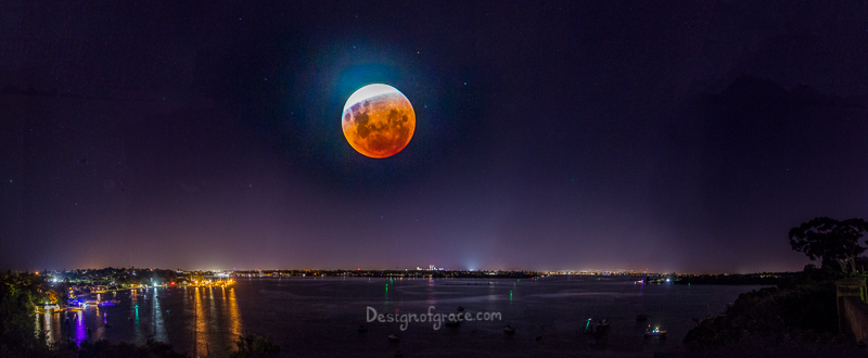 A panorama composite including the semi eclipse with the city lights below