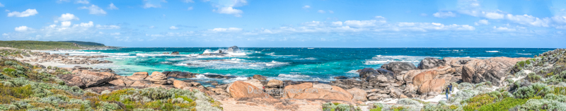 Redgate Beach Panorama, Margaret River, Western Australia with beautiful blue sky with clouds and waves crashing on the rocks with greenery around.