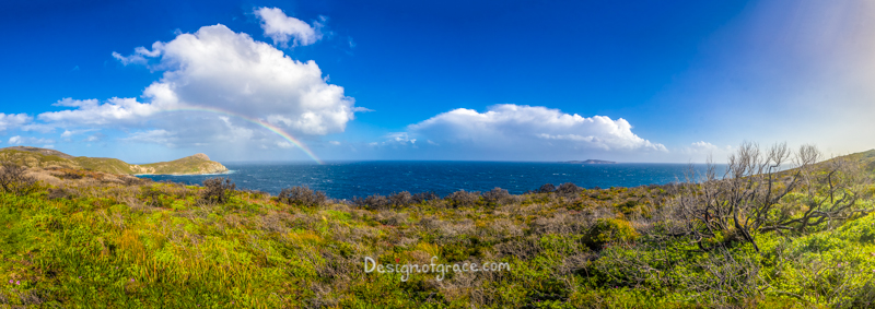 The blowholes rainbow panorama, Albany, WA with blue skies and a bit a white fluffy clouds. Green bush on the bottom