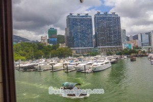 The view of high rises, big yatchs and a sampan on the water