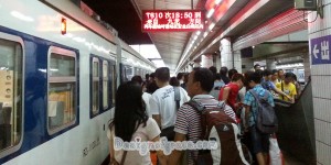 train on the left with a crowd of people on the right arriving in Guangzhou