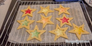 A tray of star cookies with the middle hollowed out in a star shape filled with colouful lollies unbaked