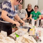 Elizabeth the presenter measuring ingredients and putting it in the mixing bowl with workshop participants watching
