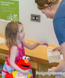 a little girl holding an elmo doll looking at the adult and handing in her bunting