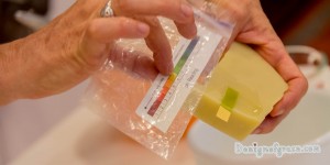 She puts a ph tester into the wet spot of the soap and compare the results with the chart which shows it has a pH level of 7 as it is showing light green.