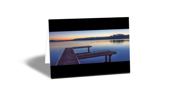 Still waters at Flathead Lake Jetty at sunset with orange and blue colours horizontal card